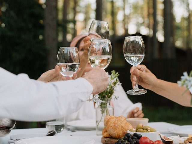 Four people chinking glasses at an outdoor dinner party